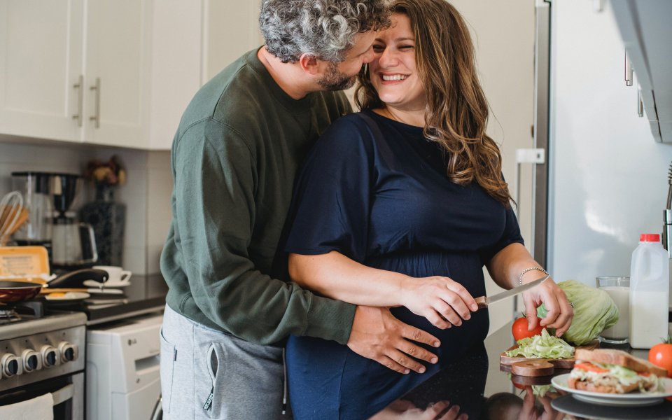 Een vader geeft een zwangere vrouw een kus