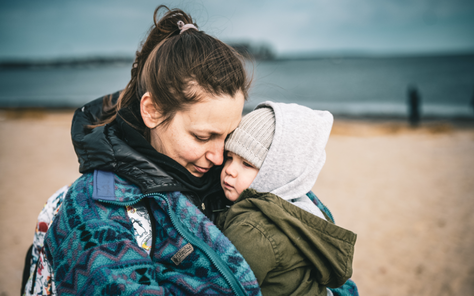 Nieuwsbericht Opgroeien Een moeder geeft haar kind een knuffel op het strand