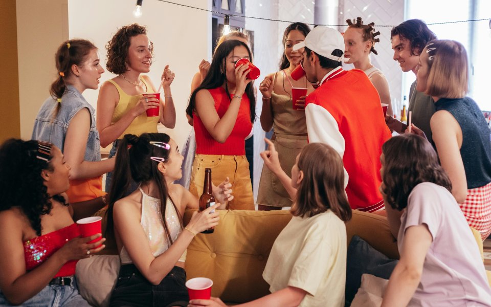 jongeren op een feestje die iemand aanmoedigen ad fundum te drinken