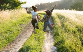 Tienermeisjes op pad, springen in de lucht, wandeling in het veld, op pad in de natuur