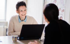 Verpleegkundige Dominique aan haar computer in overleg met een collega