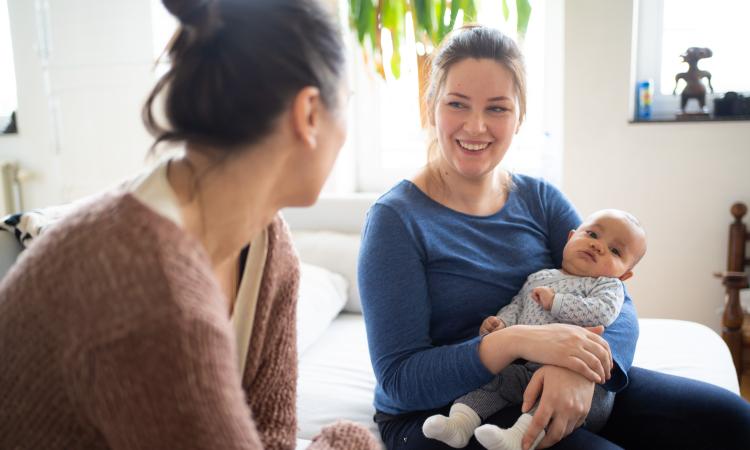Gesprek tussen een verpleegkundige en mama met baby op schoot