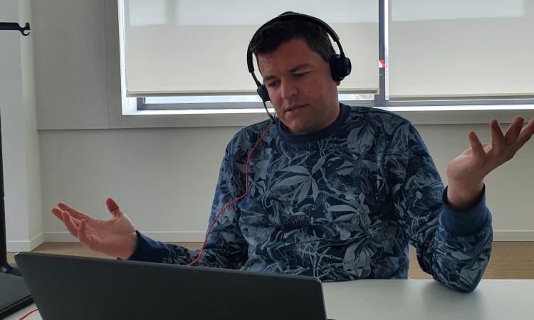 Consulent OCJ Jonas werkt aan zijn computer, videobellen met koptelefoon