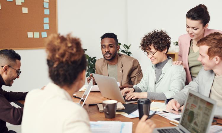 mannen en vrouwen werken samen aan tafel met laptops