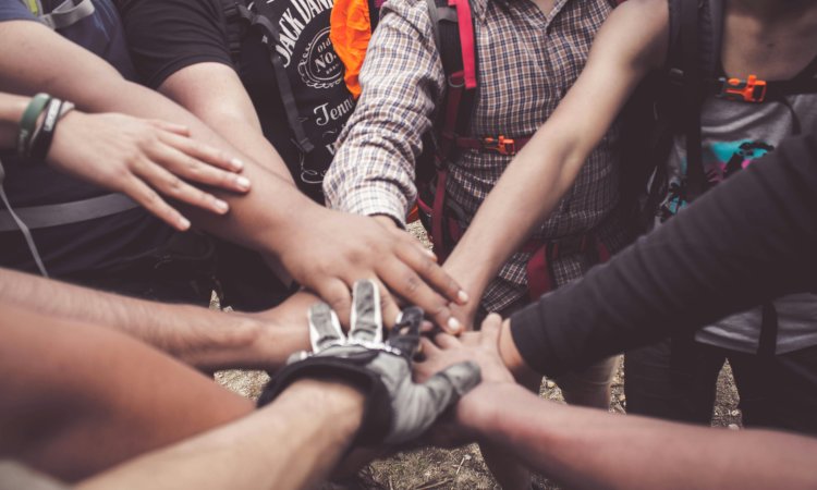 groep mensen die handen op elkaar legt in kring