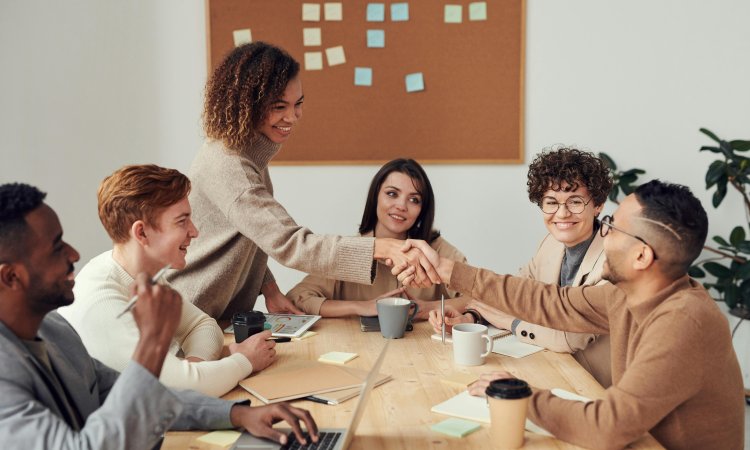 tafel-met-mensen-die-overleggen--1-vrouw-schudt-iemand-de-hand