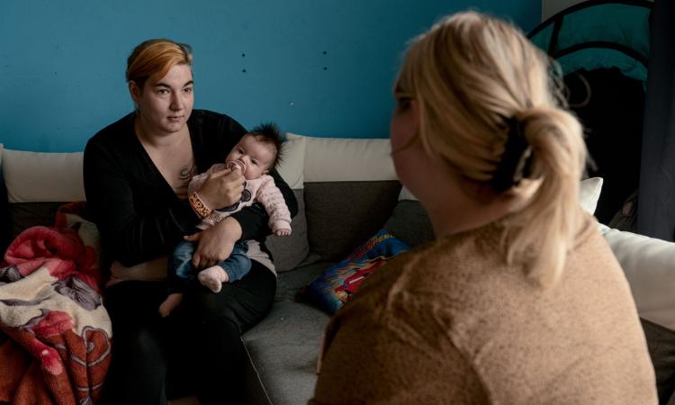 Gezinsondersteuner Melissa in gesprek met moeder die baby vasthoudt