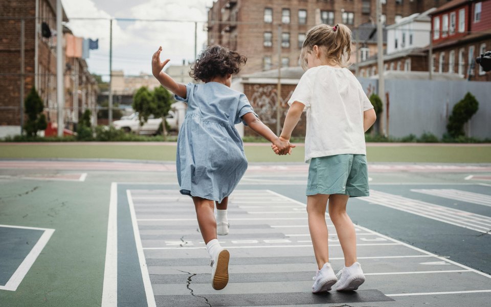 2-meisjes--hand-in-hand-springend-op-een-speelpleintje