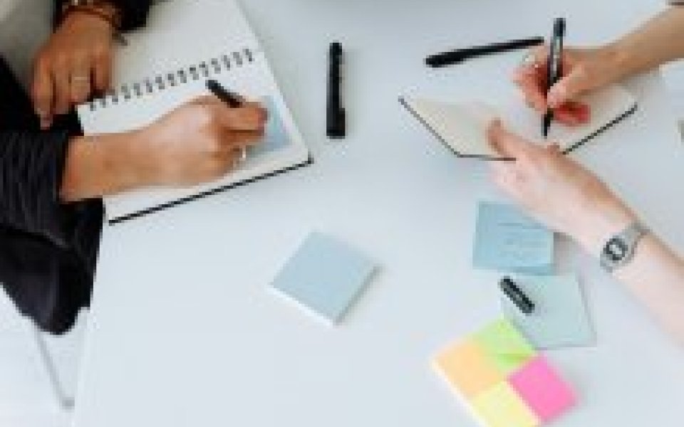 2 personen schrijven op post-its bovenaanzicht op handen