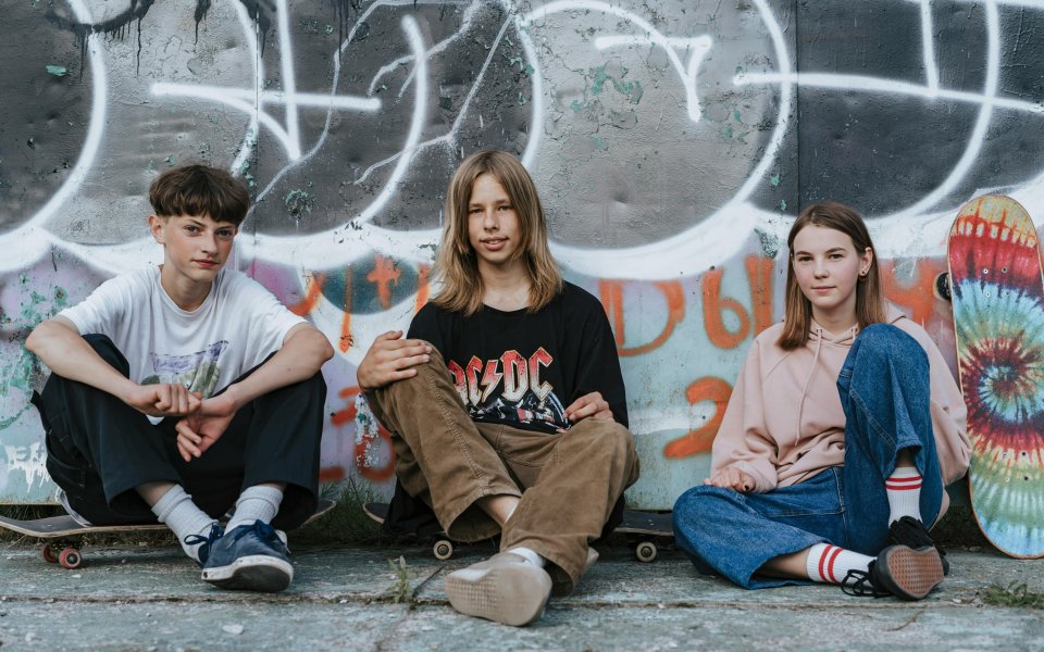 3-jongeren--zittend-tegen-een-graffiti-muur