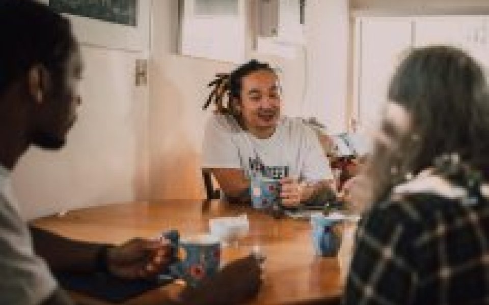 3 jongeren zitten rond een tafel met een kopje koffie