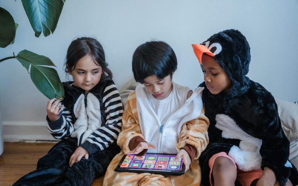 3-kinderen--in-onesie--samen-op-een-tablet-spelend
