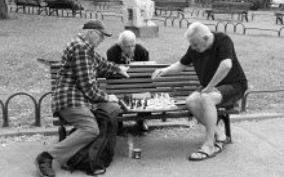 3 oudere mannen die schaken op een parkbankje