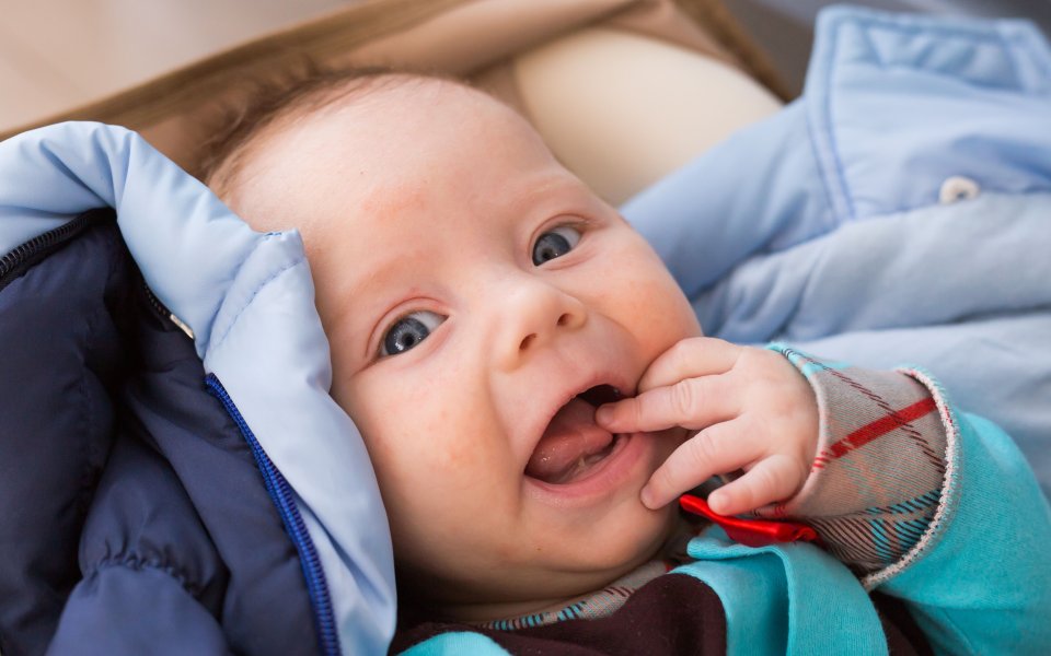baby die kijkt naar lens met mondje open, tongriem zichtbaar