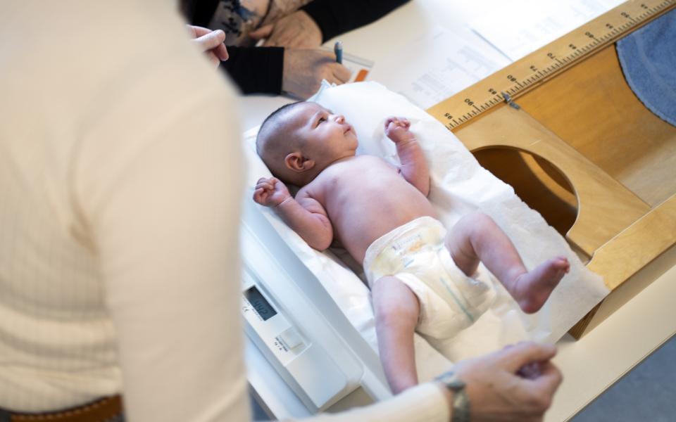 Een baby ligt op een weegschaal in een consultatiebureau van Kind en Gezin