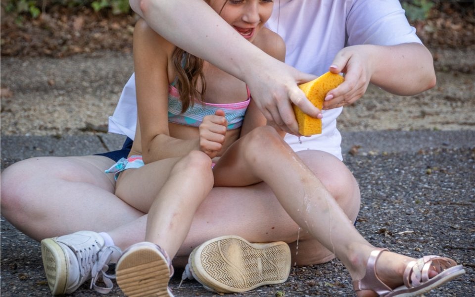 Begeleider knijpt spons uit op been van meisje