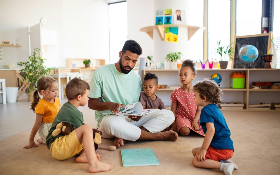 Kinderbegeleider leest een verhaal voor aan 5 kinderen in de buitenschoolse opvang