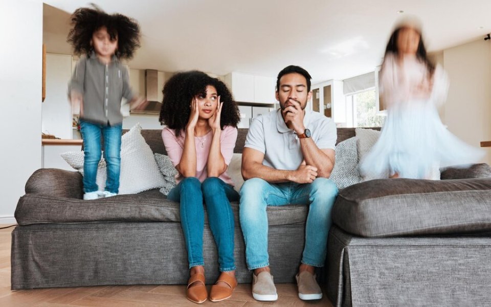 ouders zitten op zetel terwijl kinderen er op springen