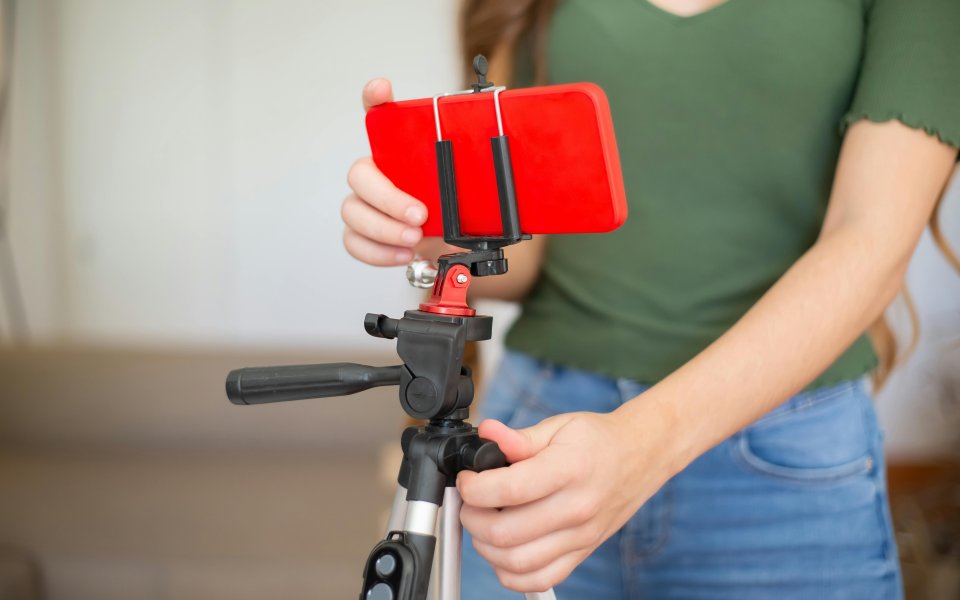 close-up-van-een-smartphone-op-een-tripot-en-de-romp-van-een-vrouw