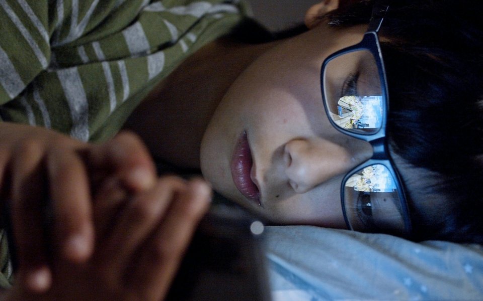 close up van een verdrietige jongen die op smartphone kijkt