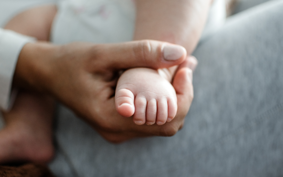 Nieuwsbericht Opgroeien Ouder houdt voet van baby vast