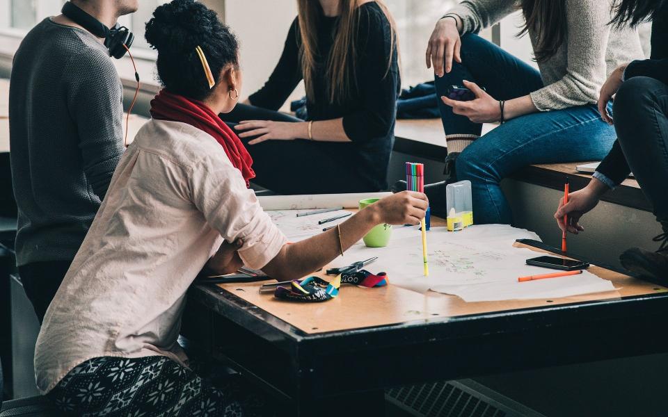 Collega's zitten samen aan tafel rond uitgetekende plannen