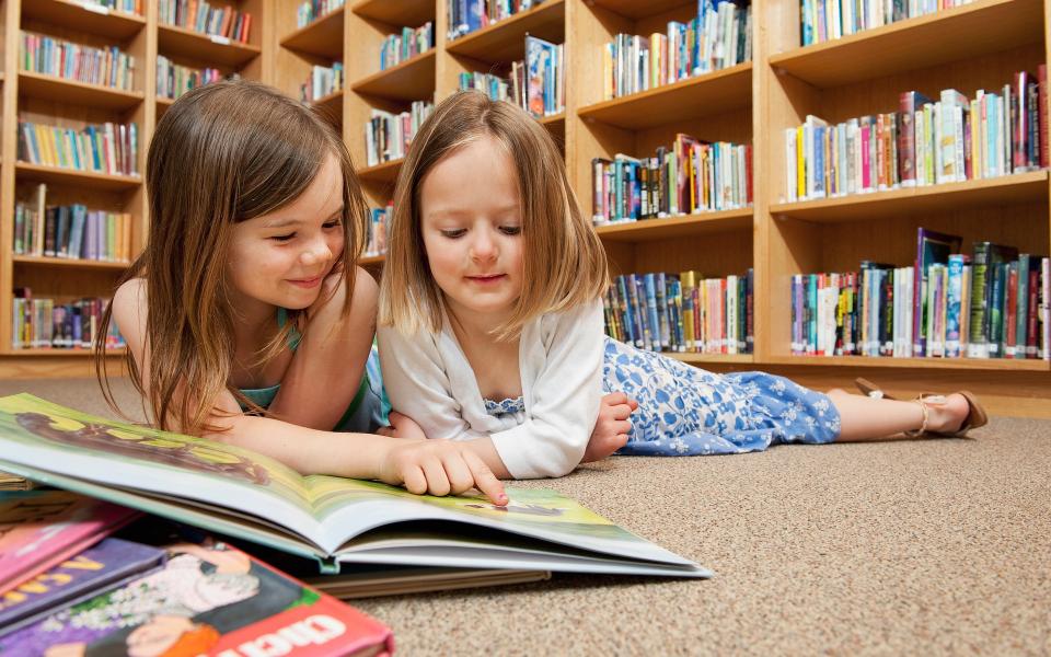 Twee meisjes lezen een kinderboek