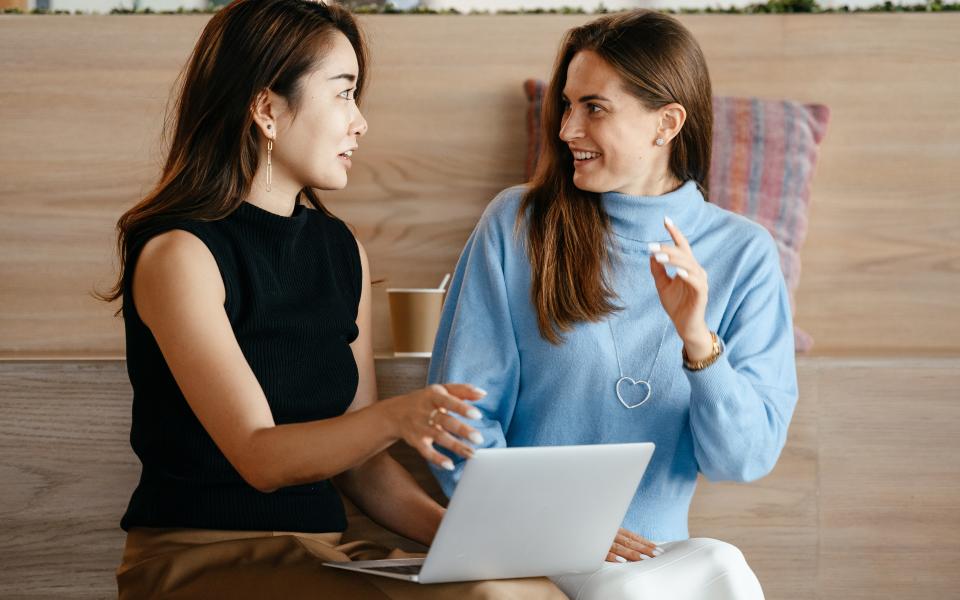 Twee vrouwen zitten neer en praten met elkaar tijdens het werk