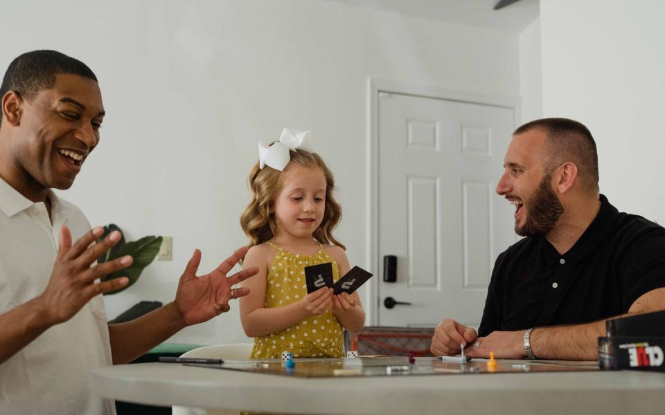 Een dochter speelt een gezelschapsspel met haar twee vaders