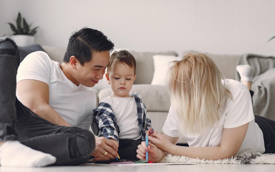 Een vader en een moeder zijn samen met een kind aan het tekenen