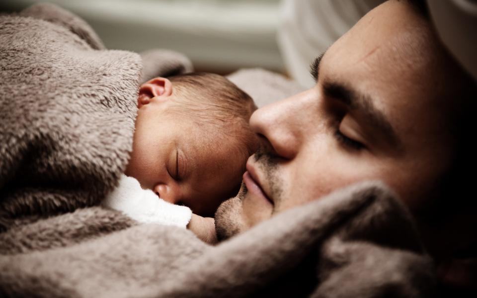 Vader slaapt met baby op zijn borst