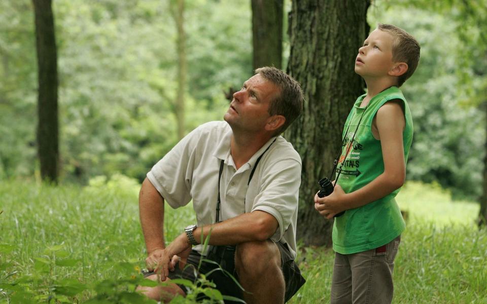 Vader en zoon kijken naar vogels in het bos