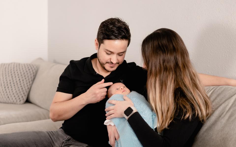 Een vader en moeder kijken naar hun baby en zitten samen in de zetel