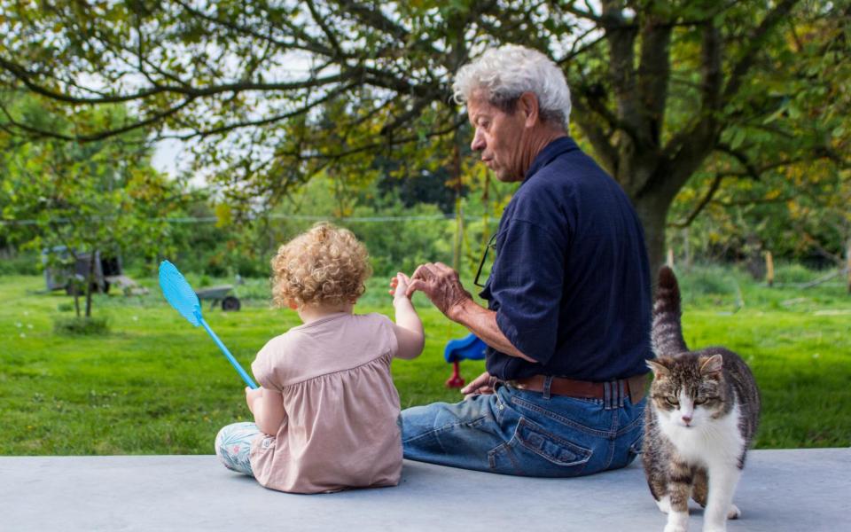 Een vader zit met zijn dochter en kat in de tuin