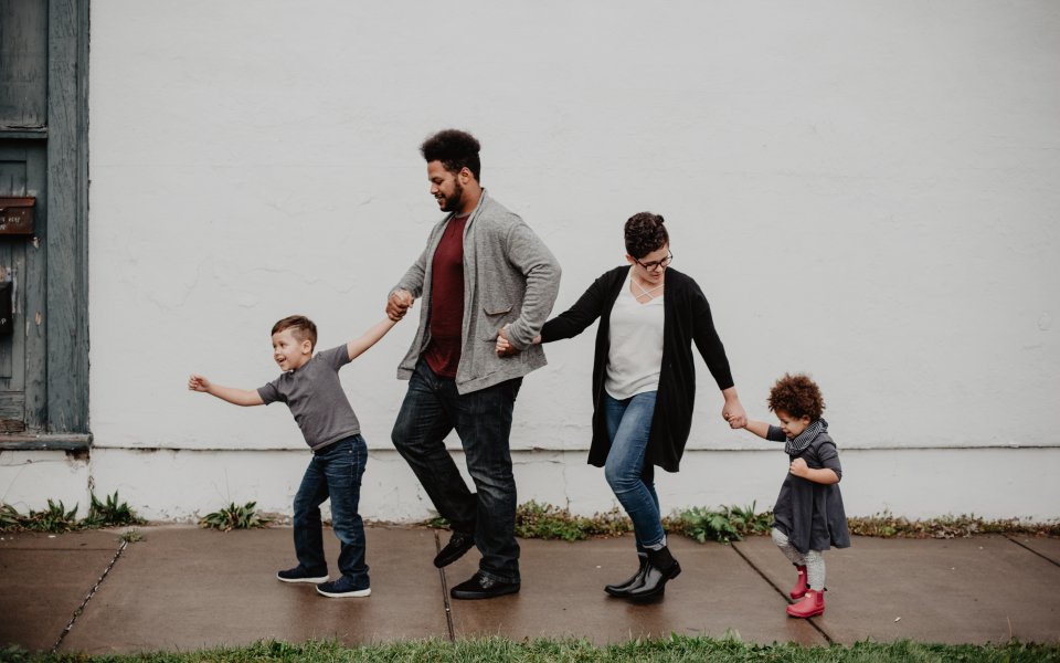 Multiculturele familie dat hand in hand over straat wandelt