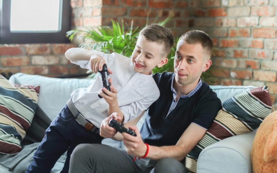 Papa en zoon gamen samen in de zetel, schermtijd thuis, vader-zoon quality time