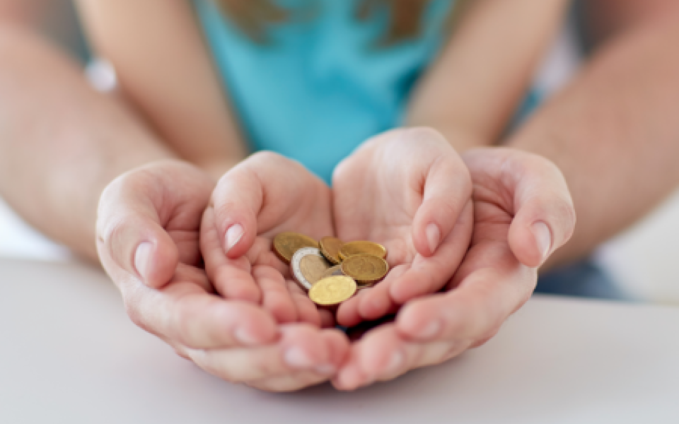 kinderhand met centjes omsloten door volwassen hand