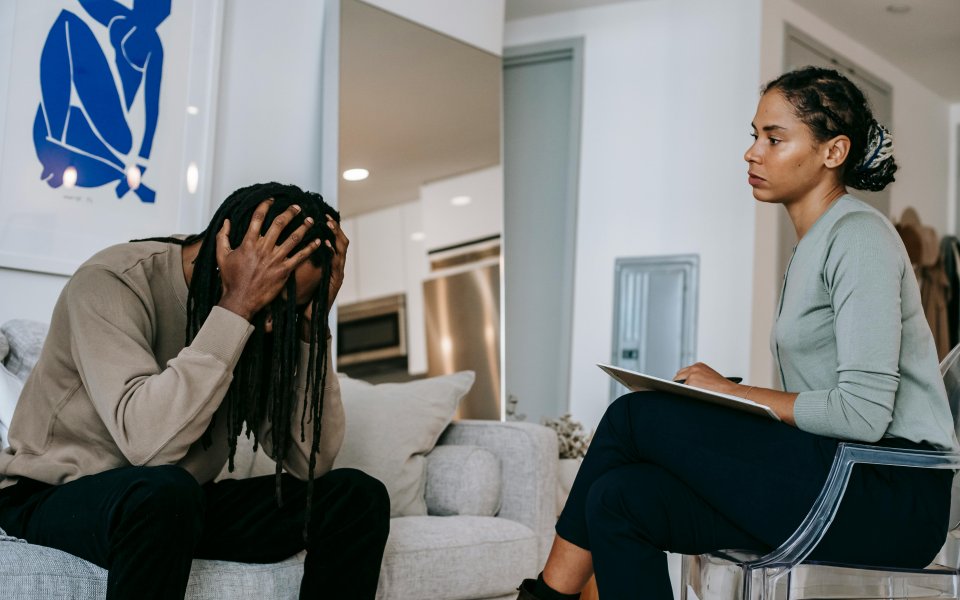 gesprek-met-jongere--die-met-zijn--hoofd-tussen-zijn-handen-voorovergebogen-zit