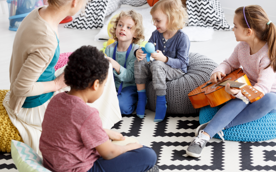 Groep kinderen en begeleider zitten samen in de kring en maken muziek