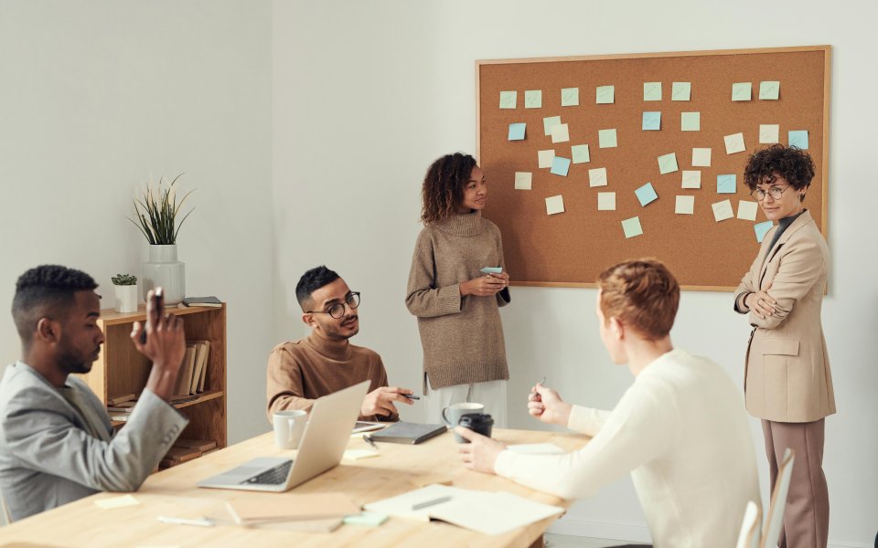 groep-mensen-aan-een-tafel-bij-een-muur-vol-post-its