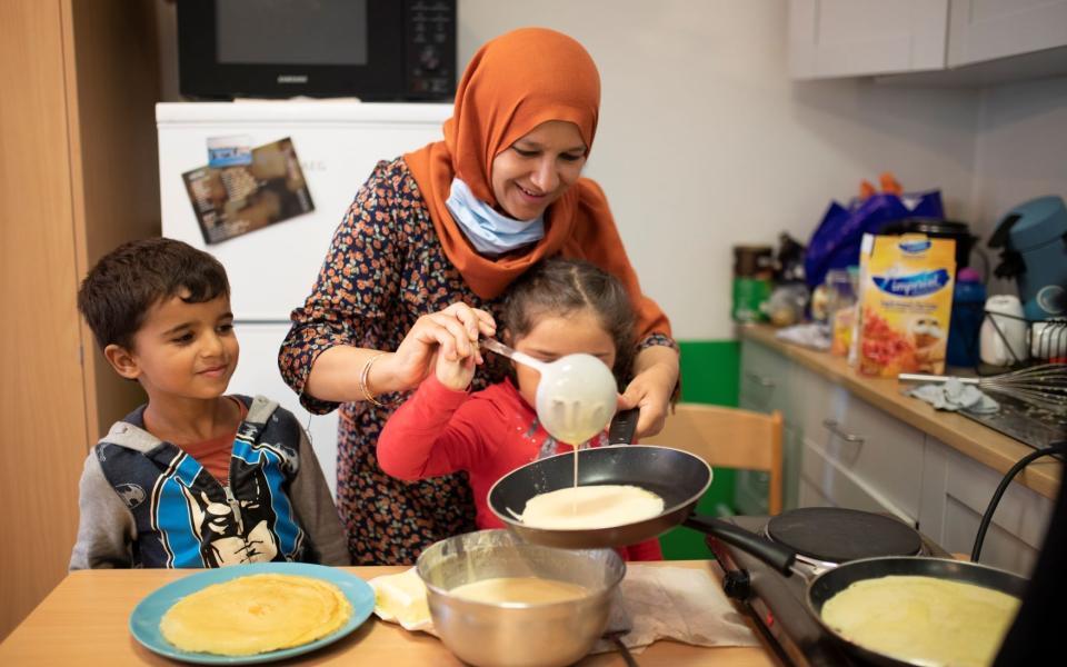 Begeleider bakt pannenkoeken samen met 2 kindjes 