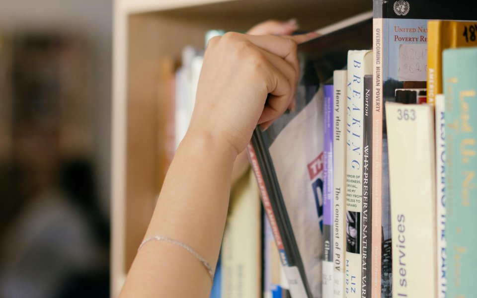 iemand neemt boek uit een rek in de bibliotheek