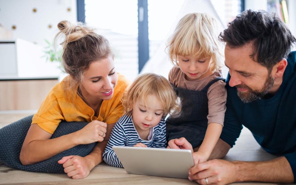 Gezin met jonge kinderen kijkt samen naar een tablet