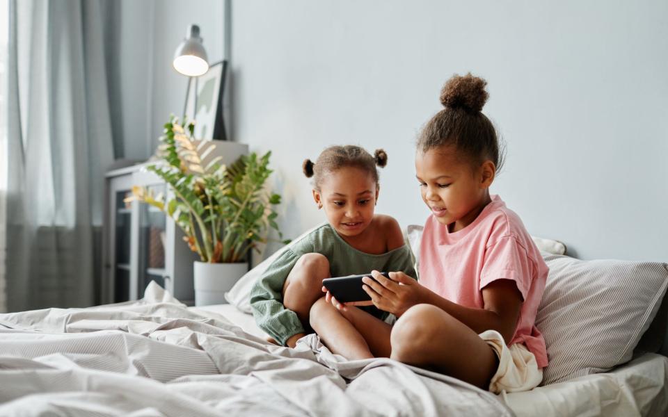 Twee jonge meisjes bekijken samen iets op smartphone in de zetel