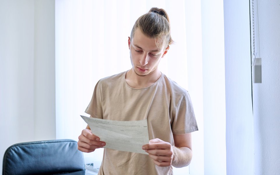 Nieuwsbericht Opgroeien Jonge man leest brief, document met serieuze uitdrukking