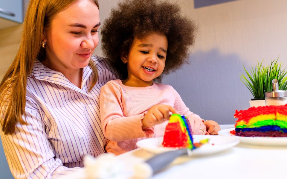 kind die speelt met cake zit op schoot bij kinderbegeleider