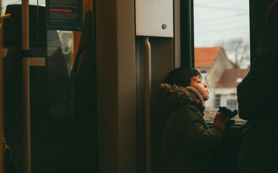 kindje staat in het openbaar vervoer en kijkt door het raam