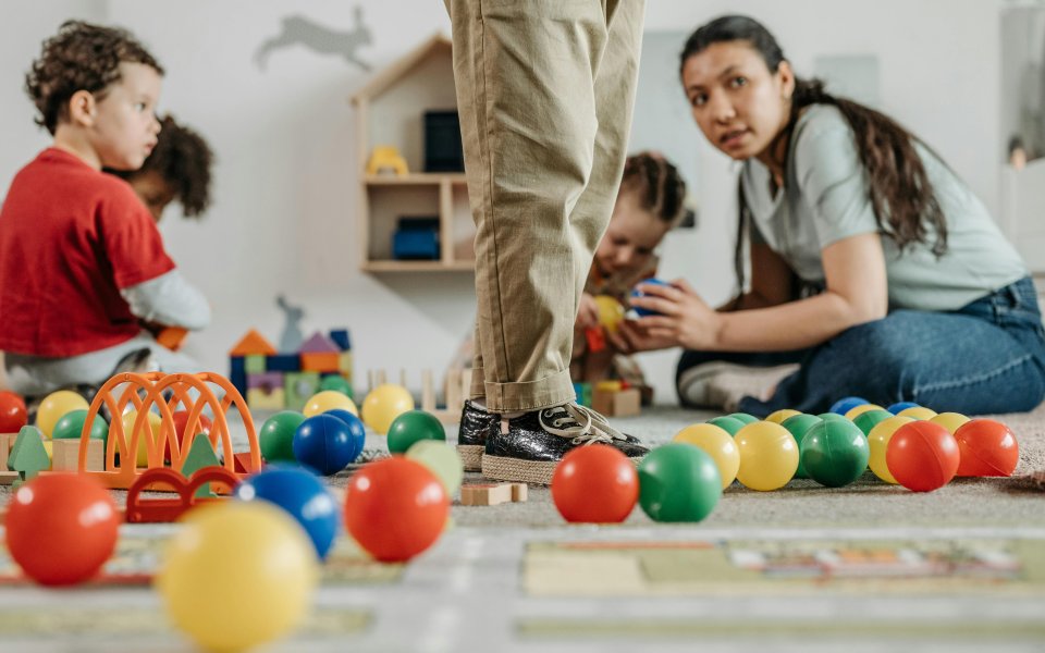 kleuterjuf-op-de-grond-zittend-tussen-de-kleuters-en-het-speelgoed