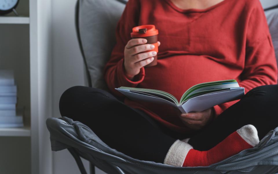 Foto van een zwangere vrouw met een boek