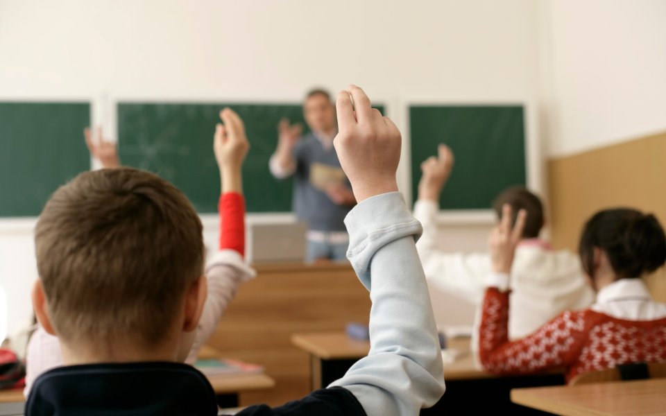 leerlingen-in-een-klaslokaal-steken-hun-hand-op-en-doen-actief-mee-met-de-les-van-de-leraar